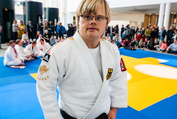 Victor Gdowczok im Judo-Anzug. Im Hintergrund Menschen und eine blaue Judo-Matte.