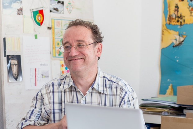 Prof. Dr. Bernhard Schmalenbach sitzt vor einem Macbook und lächelt.