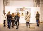 6 Personen stehen in unterschiedlichen Konstellationen zusammen und unterhalten sich. Im Hintergrund sieht man Exponate der Ausstellung.