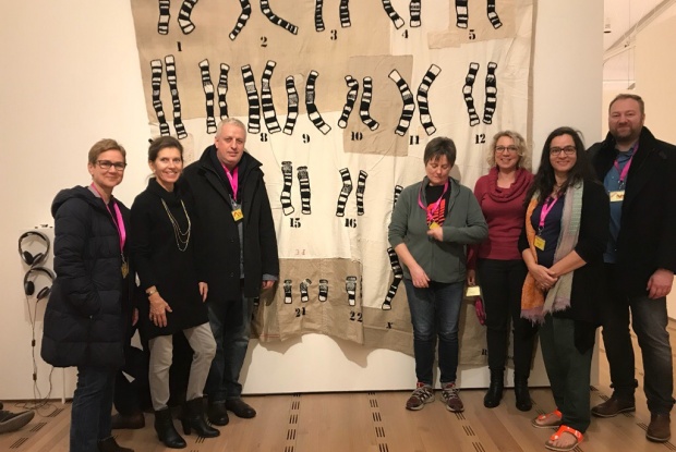 Human-Genetiker und Human-Genetikerinnen aus Bern vor dem Chromosomen-Teppich der Künstlerin Jeanne-Marie Mohn