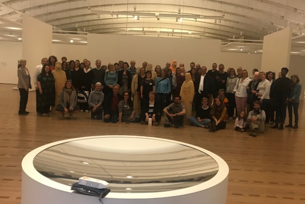 Etwa 60 Personen stehen im Eingangsbereich der Ausstellungshalle im Zentrum Paul Klee zwischen den Figuren von Markus Keuler.
