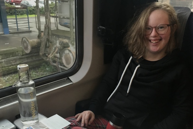 Natalie Dedreux sitzt im Zug an einem Tisch und hat ihre Notizen vor sich ausgebreitet.
